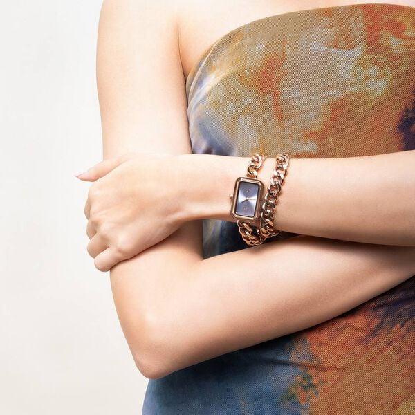 Person's arm wearing a gold bracelet with a watch on a neutral background with VYB Fastrack elegant women’s watch design