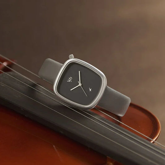 A gray Fastrack analog watch with a leather strap placed on a wooden surface, with the time displayed on the dial.